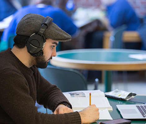 A student with headphones on taking notes